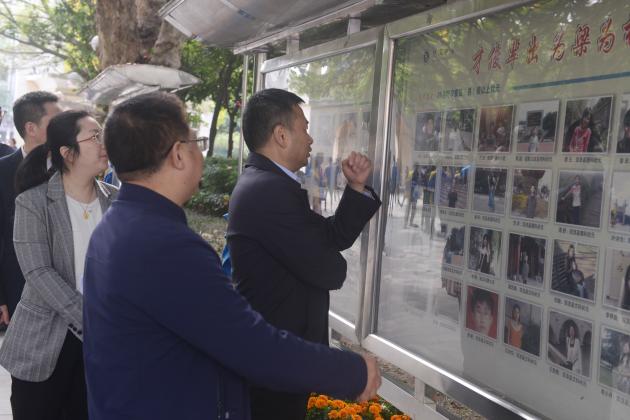 王毅部長一行在龍校長的帶領(lǐng)下參觀校園，在學(xué)校狀元榜前駐足