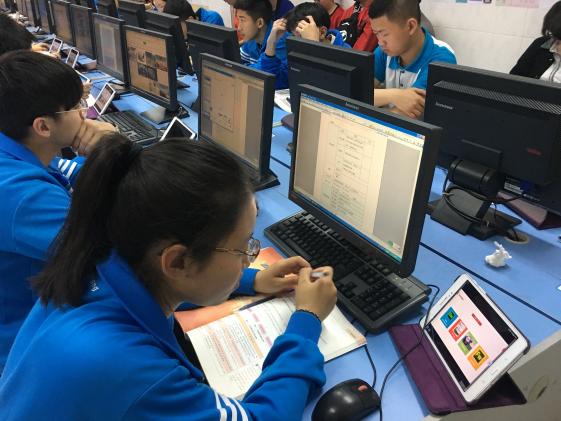  學(xué)生使用電腦、平板、教材等工具完成課堂任務(wù)